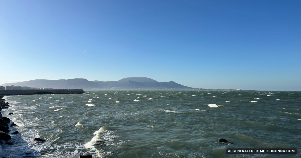Il golfo di Trieste in una giornata di vento: mare increspato con la schiuma sulle onde, un molo di pietra e l'altopiano del Carso sullo sfondo.
