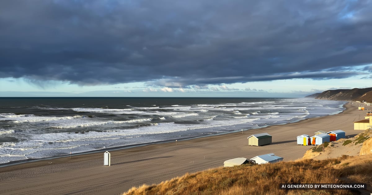 Spiaggia adriatica d'autunno con cabine chiuse, mare mosso e nuvole scure all'orizzonte con uno squarcio di sole